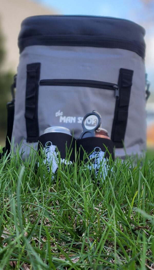 A Man Shop Cooler Backpack in the grass on a bright day.